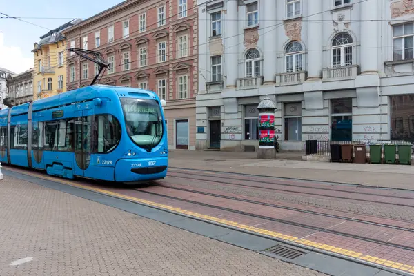 ZAGREB, CROATIA - 22 Mayıs 2025: Zagreb 'in toplu taşıma sistemine özgü canlı bir mavi modern tramvay, büyüleyici bir Avrupa kenti caddesinde süzülüyor