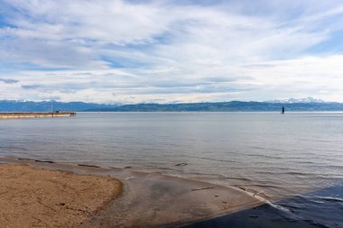 Almanya 'nın Langenargen kentinin kumlu ve çakıllı kıyılarından geniş ve sakin bir Constance Gölü manzarası uzanır.