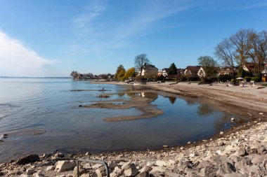 Almanya 'nın Langenargen kentindeki Constance Gölü' ndeki (Bodensee) alçak su seviyelerinin geniş ve sakin bir görüntüsü, açık ve güneşli bir günde kumlu ve çakıllı bir kıyı şeridini gözler önüne serer.
