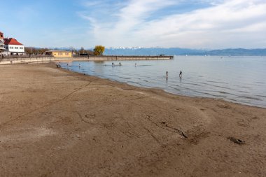 Almanya 'nın Langenargen kentinin kumlu ve çakıllı kıyılarından geniş ve sakin bir Constance Gölü manzarası uzanır.