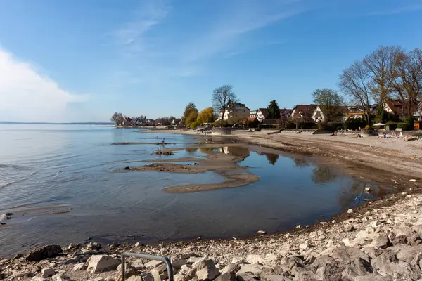 Almanya 'nın Langenargen kentindeki Constance Gölü' ndeki (Bodensee) alçak su seviyelerinin geniş ve sakin bir görüntüsü, açık ve güneşli bir günde kumlu ve çakıllı bir kıyı şeridini gözler önüne serer.