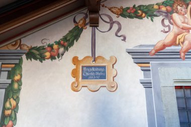 LINDAU, GERMANY - 26 HAZİRAN 2025: Lindau, Almanya 'da güzel bir tarihsel freskin ayrıntılı, düşük açılı bir çekimi, iki kanatlı putti tarafından çevrelenmiş merkezi süslemeli bir kartuş (melekler))