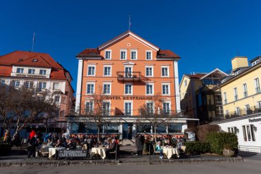 LINDAU, GERMANY - 26 HAZİRAN 2025 Lindau, Almanya 'da belirgin turuncu cephesi ve açık mavi gökyüzü altında geleneksel kırmızı kaplamalı çatısı ile 