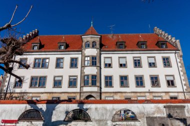 Lindau, Almanya 'da bulunan tarihi çok katlı bir binada kırmızı kiremitli bir çatı ve açık renkli bir cephe yer alıyor.