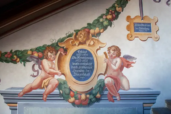 LINDAU, GERMANY - 26 HAZİRAN 2025: Lindau, Almanya 'da güzel bir tarihsel freskin ayrıntılı, düşük açılı bir çekimi, iki kanatlı putti tarafından çevrelenmiş merkezi süslemeli bir kartuş (melekler))