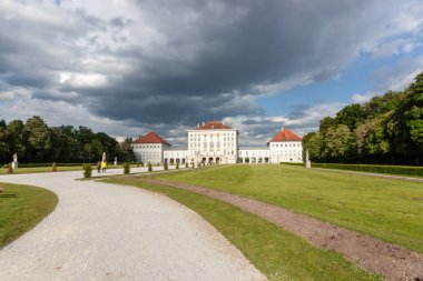Münih, Almanya 'daki ikonik Nymphenburg Sarayı' nın muhteşem, geniş açılı manzarası dramatik bulutlu gökyüzü ve parlak güneş ışığının karışımı ile yıkandı.
