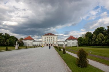 Münih, Almanya 'daki ikonik Nymphenburg Sarayı' nın muhteşem, geniş açılı manzarası dramatik bulutlu gökyüzü ve parlak güneş ışığının karışımı ile yıkandı.