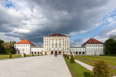Münih, Almanya 'daki ikonik Nymphenburg Sarayı' nın muhteşem, geniş açılı manzarası dramatik bulutlu gökyüzü ve parlak güneş ışığının karışımı ile yıkandı.