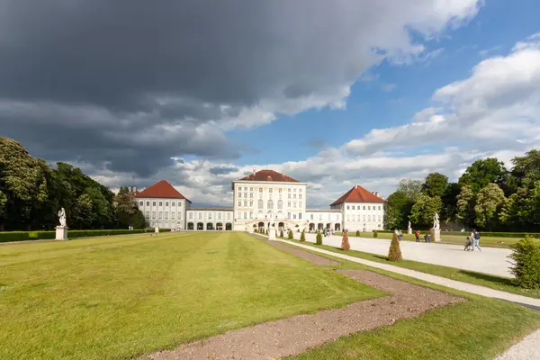 Münih, Almanya 'daki ikonik Nymphenburg Sarayı' nın muhteşem, geniş açılı manzarası dramatik bulutlu gökyüzü ve parlak güneş ışığının karışımı ile yıkandı.