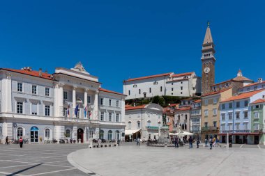 PİRAN, SLOVENIA - 19 Mayıs 2025: Piran, Slovenya 'nın canlı kalbi Tartini Meydanı' nın geniş açılı, güneşli manzarası, çarpıcı derecede açık mavi bir gökyüzü altında