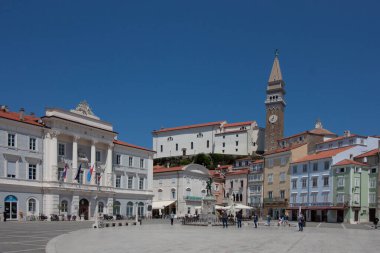 PİRAN, SLOVENIA - 19 Mayıs 2025: Piran, Slovenya 'nın canlı kalbi Tartini Meydanı' nın geniş açılı, güneşli manzarası, çarpıcı derecede açık mavi bir gökyüzü altında