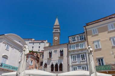 Yukarı doğru çarpıcı bir bakış açısı, Slovenya 'nın Piran kentinin büyüleyici tarihi binaları üzerinde yükselen Aziz George Kilisesi' nin ikonik Venedik çan kulesini yakalıyor.