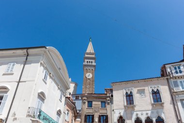 Yukarı doğru çarpıcı bir bakış açısı, Slovenya 'nın Piran kentinin büyüleyici tarihi binaları üzerinde yükselen Aziz George Kilisesi' nin ikonik Venedik çan kulesini yakalıyor.