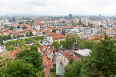 Geniş bir yükseltilmiş manzara, bulutlu bir günde Slovenya 'nın Ljubljana kentinin manzarasını yakalıyor. Kırmızı kiremitli çatılar ön plana hükmediyor ve eski kasabanın büyüleyici tarihi mimarisini gözler önüne seriyor.