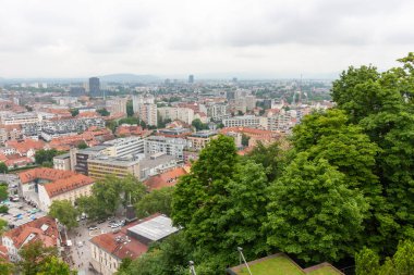 Geniş bir yükseltilmiş manzara, bulutlu bir günde Slovenya 'nın Ljubljana kentinin manzarasını yakalıyor. Kırmızı kiremitli çatılar ön plana hükmediyor ve eski kasabanın büyüleyici tarihi mimarisini gözler önüne seriyor.