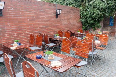 ULM, ALMANY - 30 Mart 2025: Ulm, Almanya 'da bir açık hava yemek alanı, kaldırım taşı yüzeyine dizilmiş ahşap masa ve sandalyeler içerir