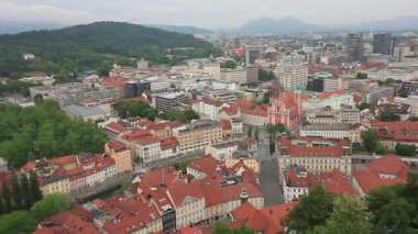 Geniş bir yükseltilmiş manzara, bulutlu bir günde Slovenya 'nın Ljubljana kentinin manzarasını yakalıyor. Kırmızı kiremitli çatılar ön plana hükmediyor ve eski kasabanın büyüleyici tarihi mimarisini gözler önüne seriyor.