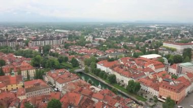 Geniş bir yükseltilmiş manzara, bulutlu bir günde Slovenya 'nın Ljubljana kentinin manzarasını yakalıyor. Kırmızı kiremitli çatılar ön plana hükmediyor ve eski kasabanın büyüleyici tarihi mimarisini gözler önüne seriyor.