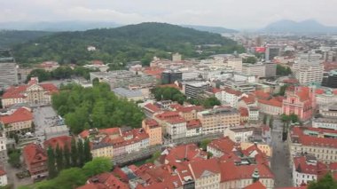 Geniş bir yükseltilmiş manzara, bulutlu bir günde Slovenya 'nın Ljubljana kentinin manzarasını yakalıyor. Kırmızı kiremitli çatılar ön plana hükmediyor ve eski kasabanın büyüleyici tarihi mimarisini gözler önüne seriyor.