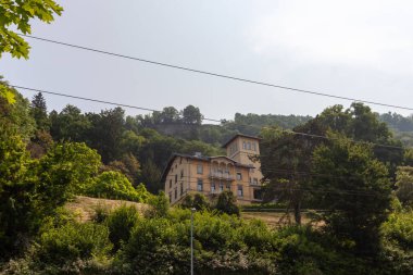 Avusturya 'nın Lochau kentindeki bir yamaçtaki yemyeşil yemyeşil yeşillikler arasında, kendine özgü bir kulesi ve kavisli pencereleri olan, sıcacık toprak tonlarıyla boyanmış, görkemli ve heybetli bir villa veya tarihi bir bina bulunur.