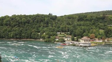 Ren Şelalesi yakınlarındaki Ren nehrinin manzarası. Tepede yemyeşil ormanlar var.