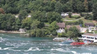 Ren Şelalesi 'nin yakınındaki Ren Nehri' nin yakın görüntüsü rıhtıma yanaşmış ya da hareket halindeki birkaç turist teknesini gösteriyor.