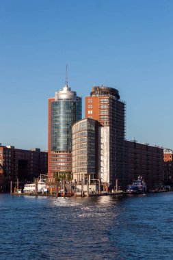 HAMBURG, GERMANY - 12 AĞUSTOS 2024: Hamburg, Almanya 'daki modern yüksek binaların liman manzarası, açık mavi bir gökyüzü altında