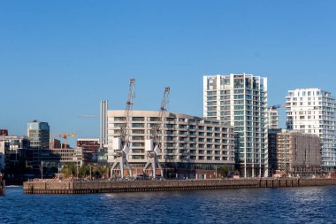 HAMBURG, GERMANY - 12 AĞUSTOS 2024: Hamburg 'daki Elbe Nehri kıyısı boyunca yer alan modern yerleşim ve ticari binaların panoramik manzarası
