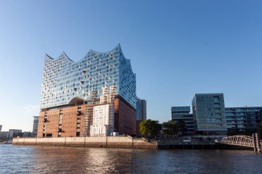 HAMBURG, GERMANY - 12 AĞUSTOS 2024: Modern Elbphilharmonie konser salonu Hamburg 'daki Elbe nehrinde belirgin bir şekilde duruyor.