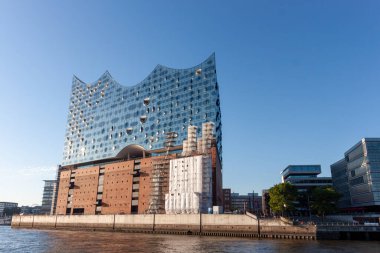 HAMBURG, GERMANY - 12 AĞUSTOS 2024: Modern Elbphilharmonie konser salonu Hamburg 'daki Elbe nehrinde belirgin bir şekilde duruyor.