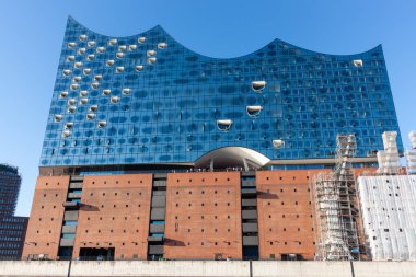 HAMBURG, GERMANY - 12 AĞUSTOS 2024: Hamburg 'daki sembolik Elbphilharmonie konser salonunun düşük açılı görüntüsü, etkileyici cam cephesini ve tuğla taban görüntüsünü gözler önüne seriyor