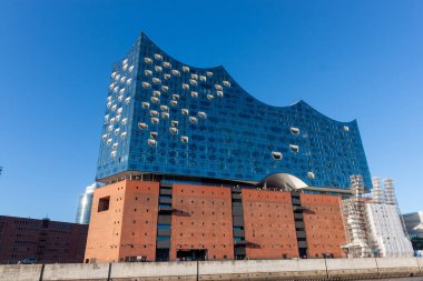 HAMBURG, GERMANY - 12 AĞUSTOS 2024: Hamburg 'daki sembolik Elbphilharmonie konser salonunun düşük açılı görüntüsü, etkileyici cam cephesini ve tuğla taban görüntüsünü gözler önüne seriyor