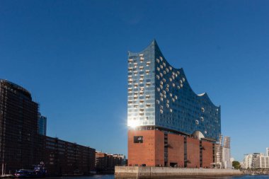 HAMBURG, GERMANY - 12 AĞUSTOS 2024: Elbphilharmonie konser salonunun çarpıcı modern mimarisi Hamburg 'daki tarihi tuğla depo binasının yanında duruyor