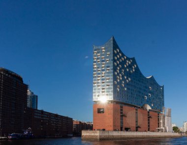 HAMBURG, GERMANY - 12 AĞUSTOS 2024: Elbphilharmonie konser salonunun çarpıcı modern mimarisi Hamburg 'daki tarihi tuğla depo binasının yanında duruyor