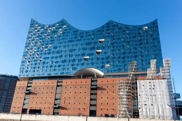HAMBURG, GERMANY - 12 AĞUSTOS 2024: Hamburg 'daki sembolik Elbphilharmonie konser salonunun düşük açılı görüntüsü, etkileyici cam cephesini ve tuğla taban görüntüsünü gözler önüne seriyor