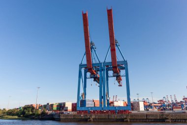 HAMBURG, GERMANY - 12 AĞUSTOS 2024: Hamburg limanındaki iki büyük, modern konteyner vincinin çarpıcı düşük açılı görüntüsü