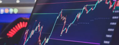 Karanlık bir ortamda yükselen finansal veriler ve teknik göstergelerle bir şamdan grafiğini gösteren dijital ekrana yakınlaş.