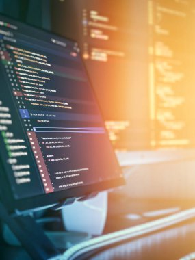 Dikey monitör, modern yazılım geliştirme, kodlama verimliliği ve dijital odağı sembolize eden güneş ışığında çalışan bir teknoloji ofisinde Python kodunu gösteriyor..