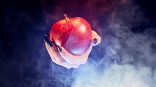 魔女としての女性は赤いリンゴを提供しています 毒性提案の象徴 おとぎ話 白い雪 ウィザードの概念 ハロウィンお祝いコスプレ 煙霧の背景 高品質4K映像 — ストック動画