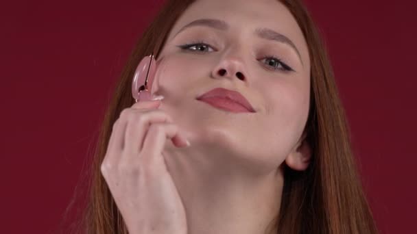 Ginger Woman Doing Face Massage Rose Quartz Stone Roller Red — Stock Video