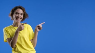 Kadın sağ tarafı işaret ediyor, kopyalama alanı. Gülümseyen bayan reklamınız için boş bir yere işaret ediyor. Kadın sunumu, mavi arka planda izole bir şey gösteriyor. Yüksek kalite 4k görüntü