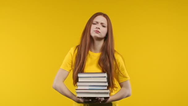 姜汁女学生对黄色背景下的大量书本作业感到不满 长发女孩很不高兴 学习使她烦恼 高质量的4K镜头 — 图库视频影像