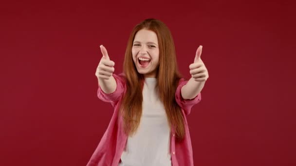 きれいな女性は 親指をジェスチャーのように手のサインをします 幸せな女の子 正しい完璧な選択 大きな取引 赤の背景 肯定的な女性のカメラ 信頼の概念に笑顔 高品質4K映像 — ストック動画