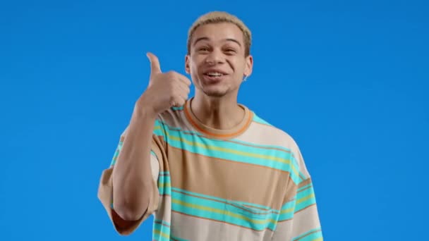 ハンサムな男は 親指をジェスチャーのように手のサインをします 幸せな男 正しい完璧な選択 大きな取引 青の背景 肯定的な男性モデルは カメラ 信頼の概念に笑顔 高品質4K — ストック動画