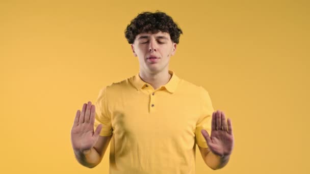 落ち着いた男はリラックスし 瞑想し ストレスを拒否します 彼は深く呼吸し 黄色のスタジオの背景に落ち着いています ヨガバランス禅の概念 高品質4K映像 — ストック動画