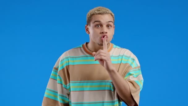 Усміхнений Чоловік Тримає Палець Губах Синій Студійний Фон Жест Таємниці — стокове відео
