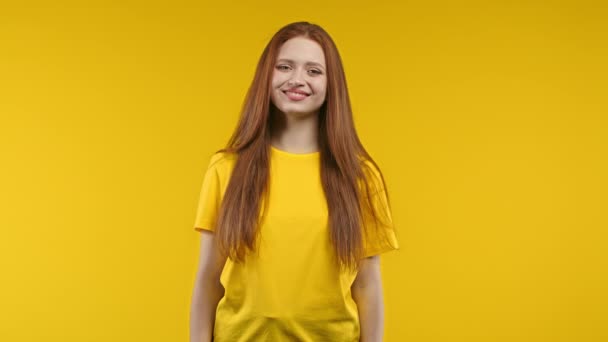 黄色のスタジオの背景にカメラに笑みを浮かべてかなり生姜の女性 長い素晴らしい髪のかわいい女の子の肖像画 高品質4K映像 — ストック動画