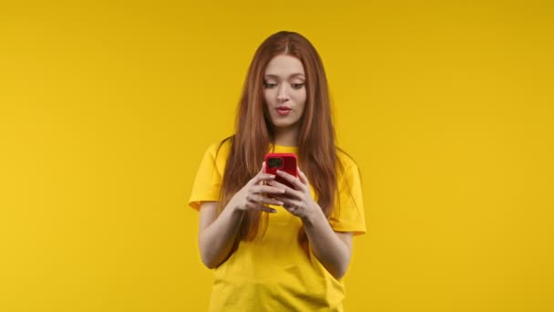 きれいな女性はスマートフォンですごいメッセージを受けました 黄色の背景に驚きと喜びを持つ女の子 幸福の概念 高品質4K映像 — ストック動画