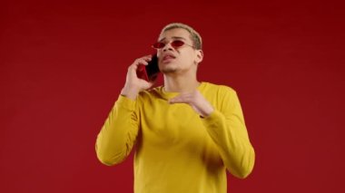 Karizmatik bir adam arkadaşıyla telefonla konuşur, uzaktan iletişim kurar, güzel şakalar yapar, kırmızı arka planda güler. Telefon görüşmesi. Yüksek kalite 4k görüntü