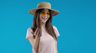 Ergen ona katılmayı teklif ediyor, el sıkışma hareketi ile işaret ediyor. Gülümseyen Asyalı kadın arıyor - Hey sen, buraya gel. Oyuncu, çapkın, davetkar. Mavi stüdyo geçmişi. kalite 4k